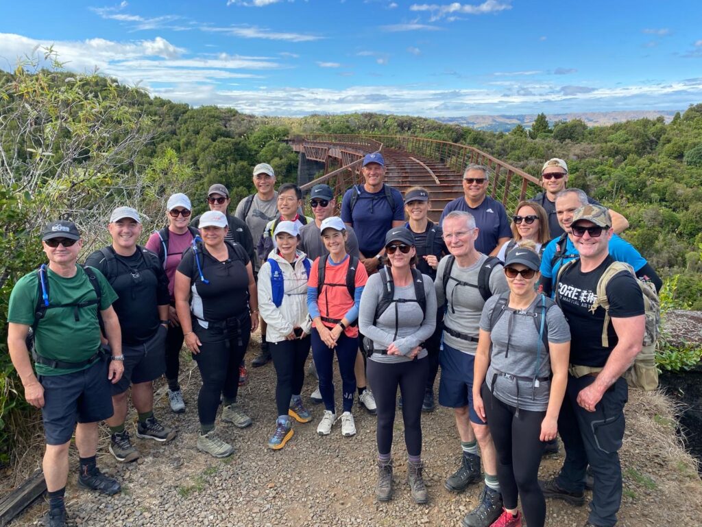 A group of hikers on a guided walk in the Tongariro National Park stand in front of the Old Hapuawhenua Viaduct on the Old Coach Road hiking track