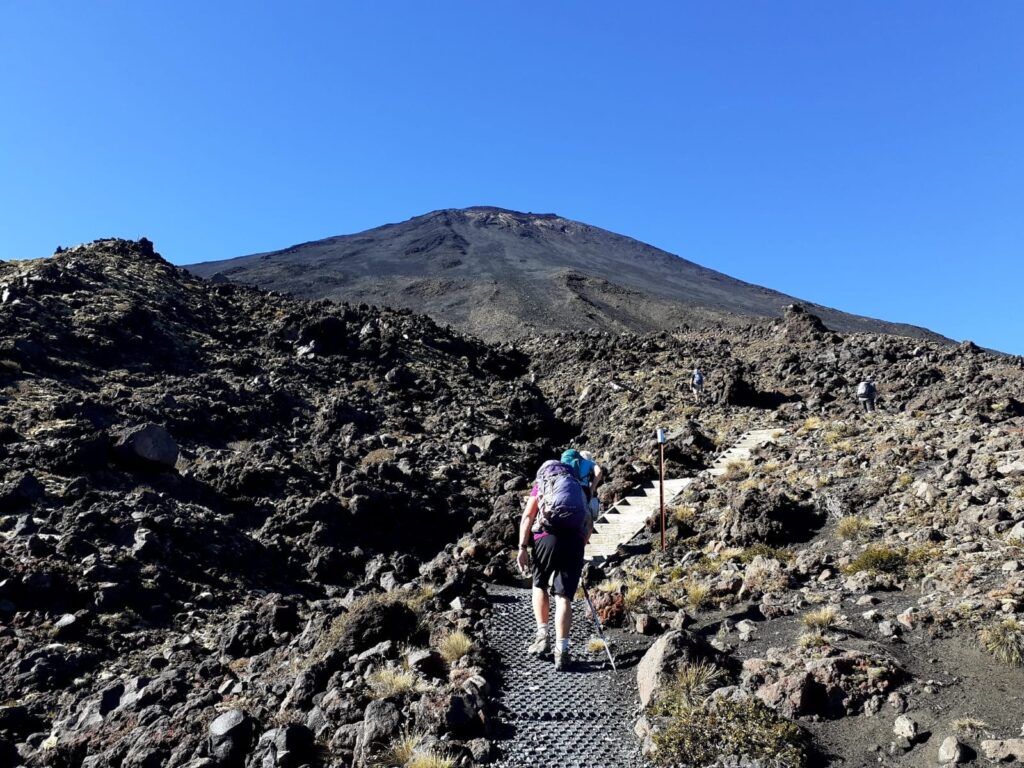 A hiker ascends the Devils Staircase on the Tongariro Alpine Crossing track on a guided walk