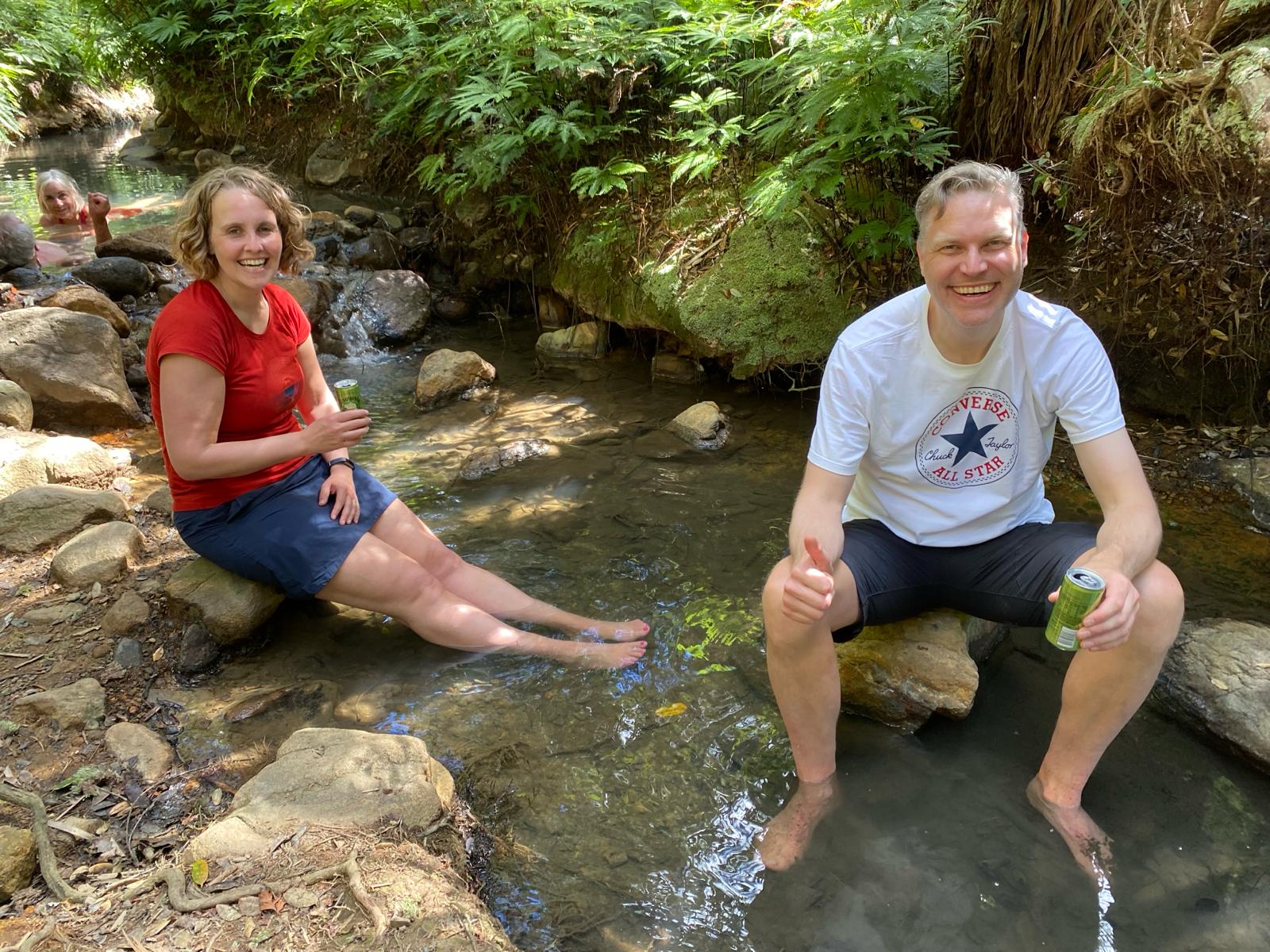 Two hikers soaking their feet in Kaitoke Hot Springs at the end of the Aotea Track on Great Barrier Island