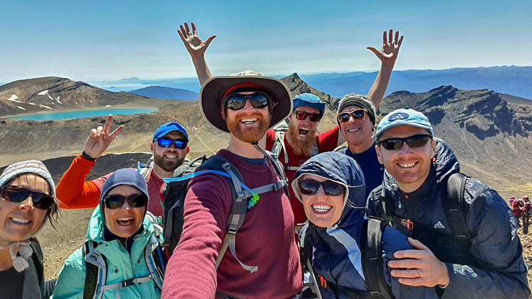 A group of hikers celebrate completing the Tongariro Alpine Crossing guided hike with Walking Legends