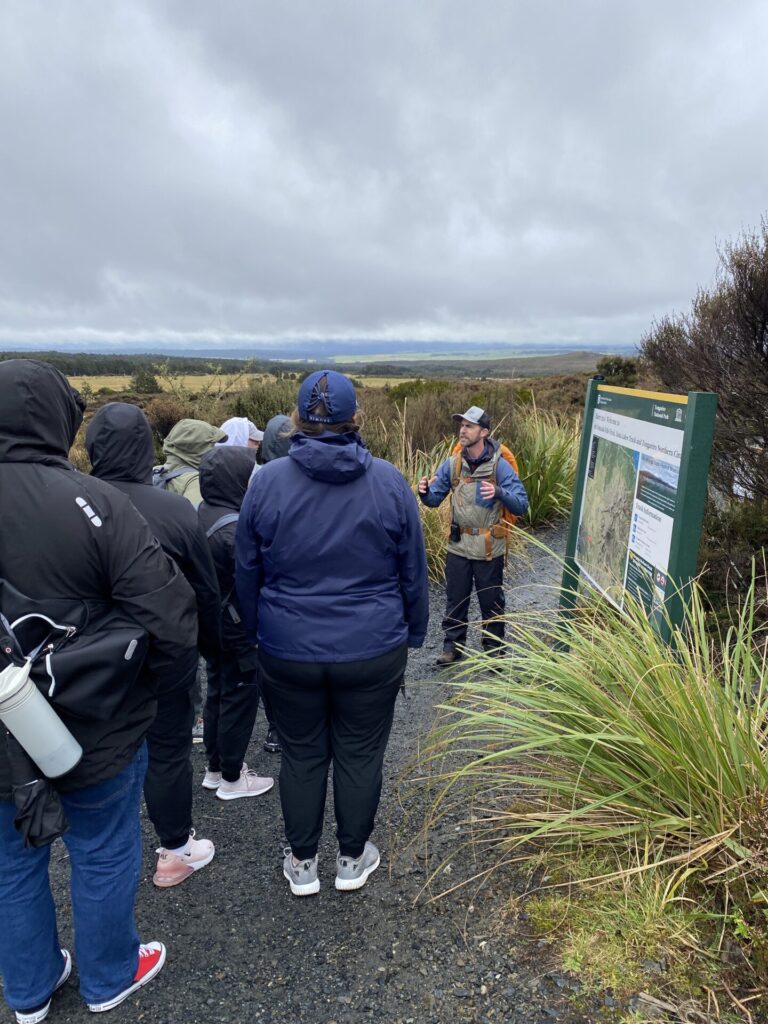 An NZ hiking guide delivers a pre-walk safety briefing to a group of hikers in the Tongariro National Park