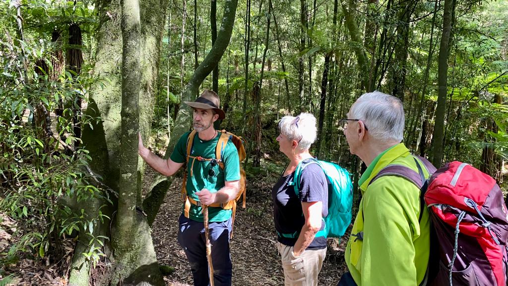 A Walking Legends hiking guide delivers an environmental education talk to a pair of guided walking guests