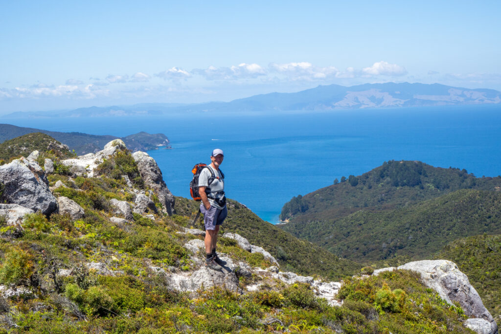 Male hiker on Great Barrier Island looks out across the Hauraki Gulf on a guided hike with Walking Legends