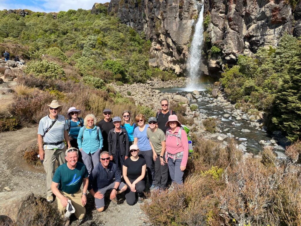 A group of hikers gather in front of Taranaki Falls, a 20 metre high, single-drop waterfall on the Tongariro Northern Circuit track, near Whakapapa, Ruapehu New Zealand