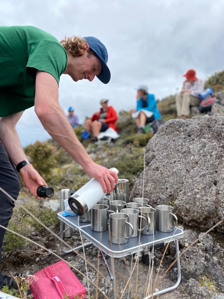 Walking Legends guide serves guests hot drinks on outdoor hiking trail in New Zealand