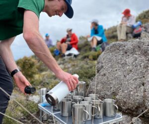 Walking Legends guide serves guests hot drinks on outdoor hiking trail in New Zealand